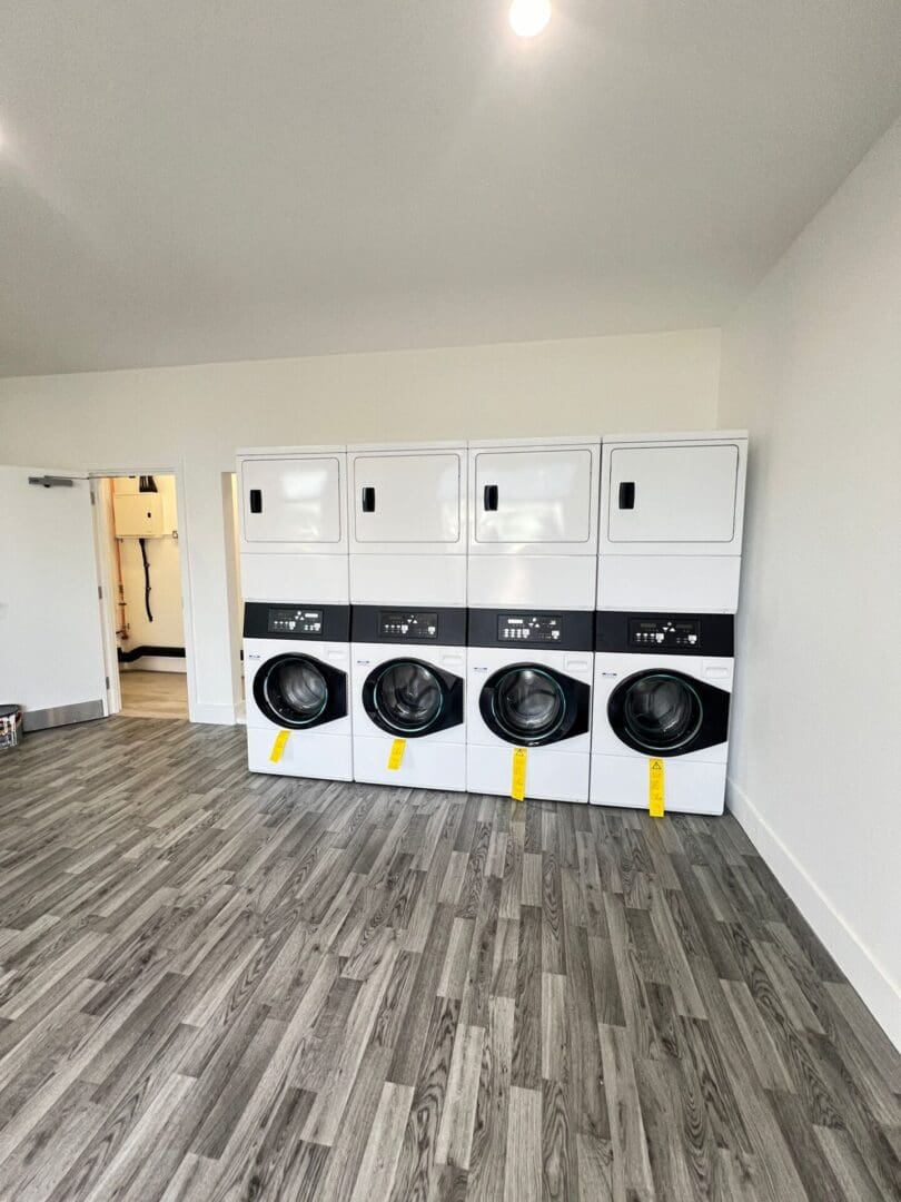 Four stacked washers and dryers in room.