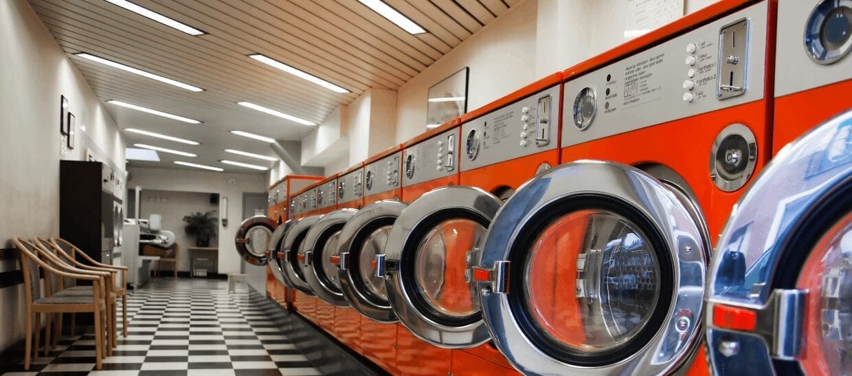 Laundromat with orange washing machines, checkered floor.