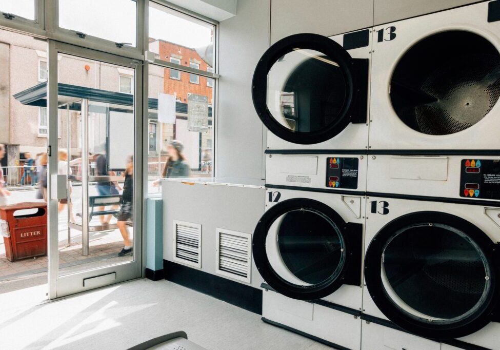 Modern laundromat with stacked white washers and dryers in natural light.